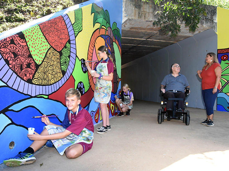 Bentley Park College Year 8 students (from left) James Threadingham, Ashlee Neiwand-Thomas and Hannah Tynan, with Division 2 Councillor Rob Pyne and artist Sharon Wedel at the newly painted Sinclair Miller Bridge underpass mural.