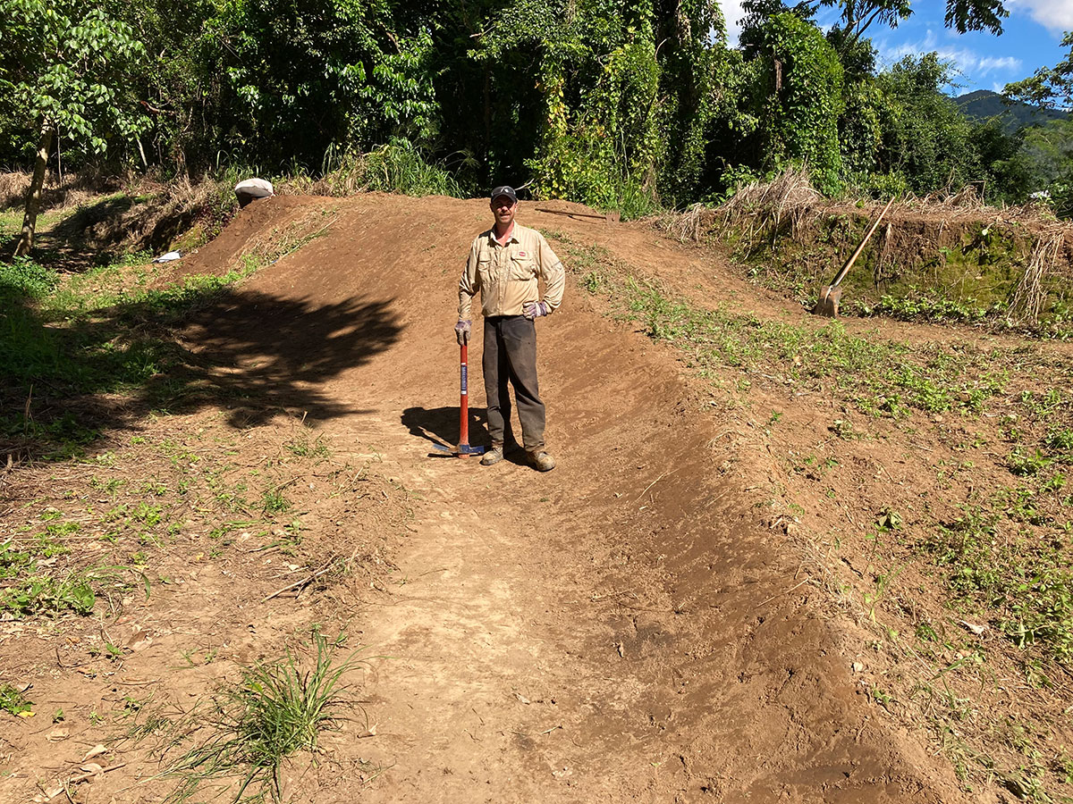 Man leaning on pick on dirt bicycle berm