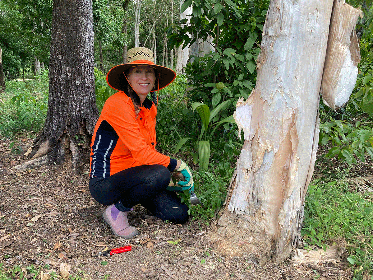 Female Egret volunteer squatting in front of tree