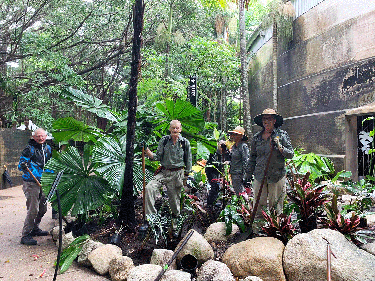 Volunteers replanting a flower bed outside the historic Tank 4