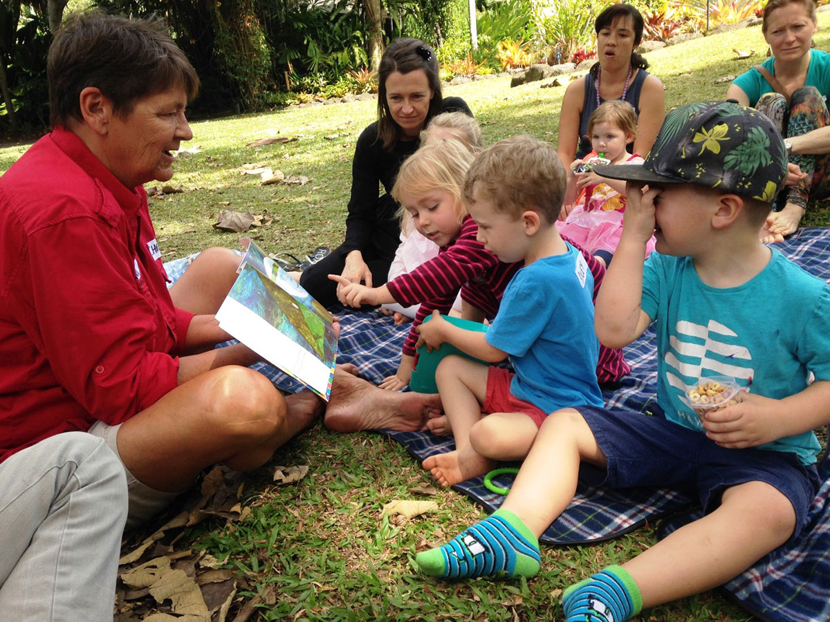 Volunteer reading book to young children in the Cairns Botanic Gardens