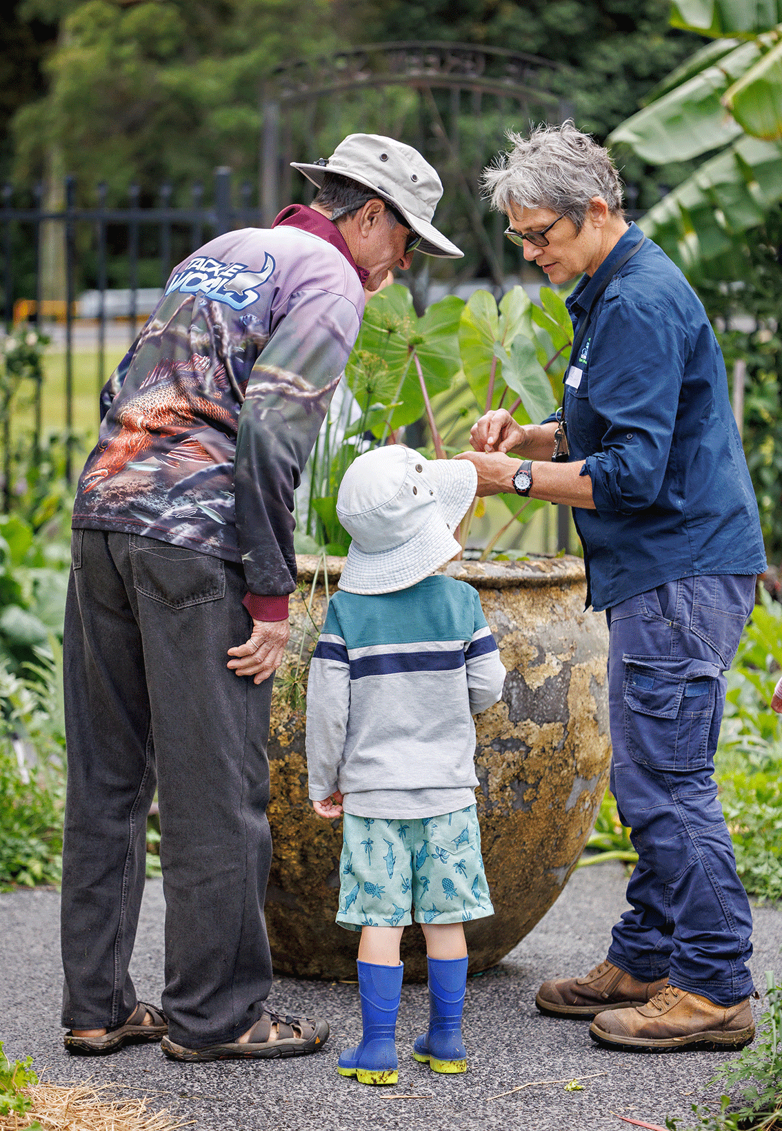 Grandfather and grandson investigate discuss plants with volunteer officer