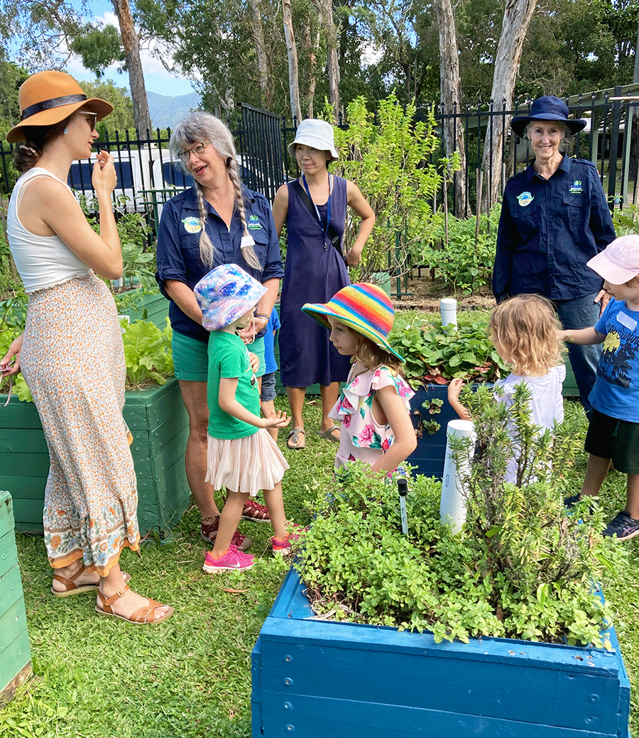 Parents, volunteers and children chat about planting in the wicking bed area of The Green Space