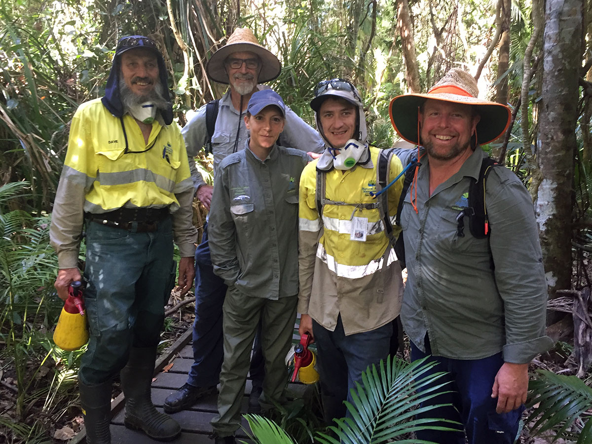 Group of 5 volunteers standing on pathway surrounded by rainforest