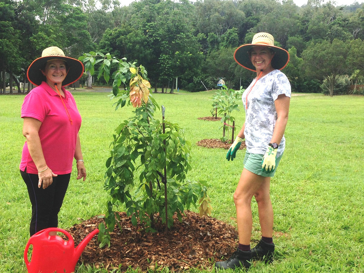 Two women inspect sapling planted to improve local park