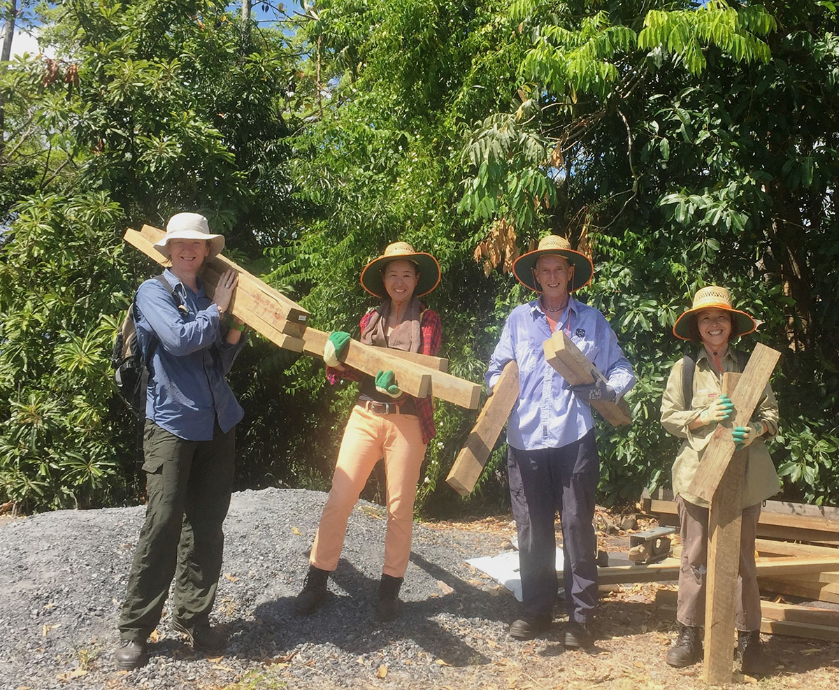 Four volunteers pose holding wood planks