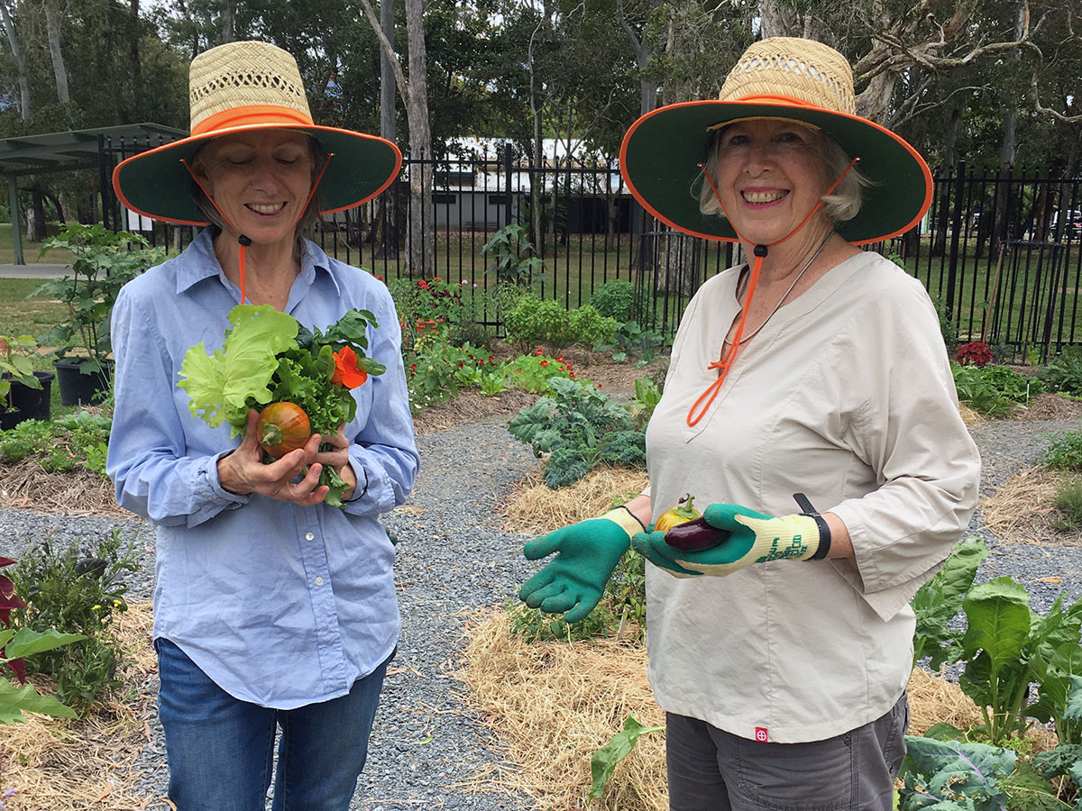 Two female volunteers hold vegetables grown in The Green Space produce garden