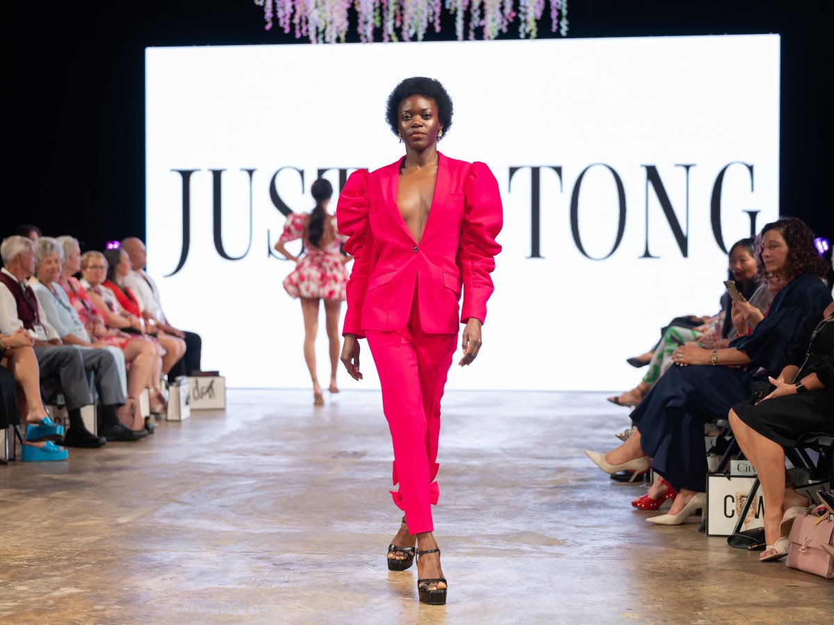 A model walks the runway, showcasing a vibrant pink suit with puffed sleeves