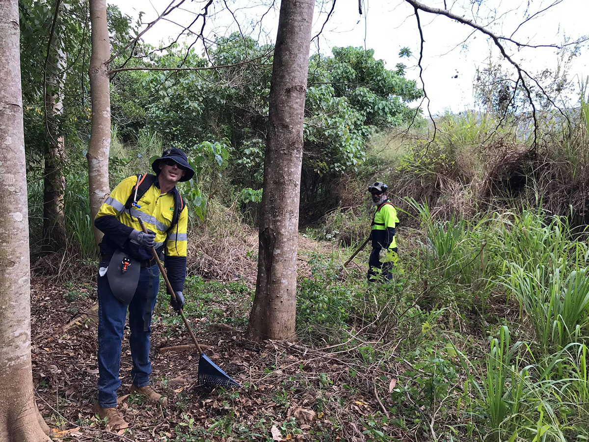Two volunteers raking undergrowth