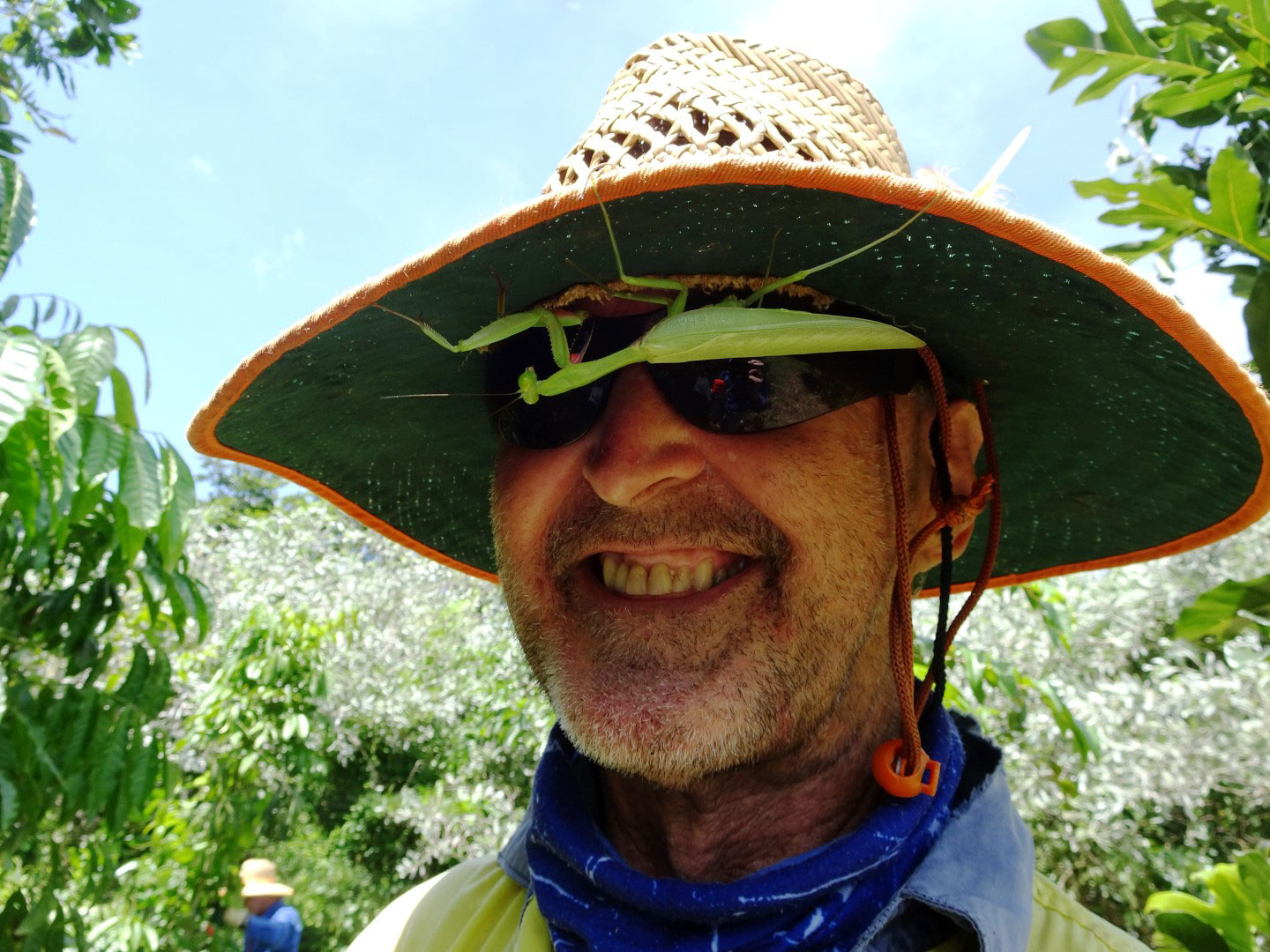 Volunteer with large grasshopper upside down on hat brim