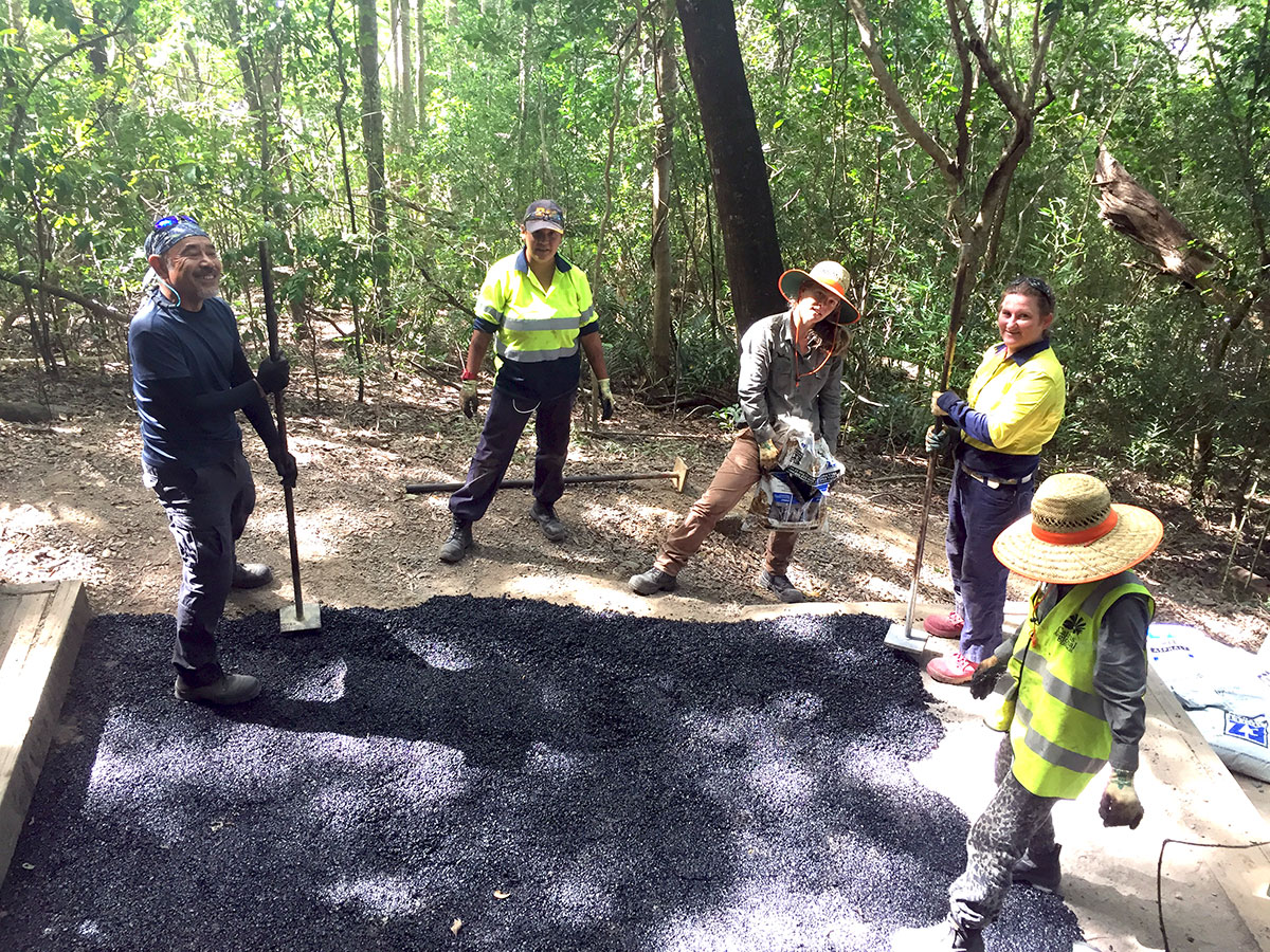 Five volunteers applying asphalt surface to Arrow Trail