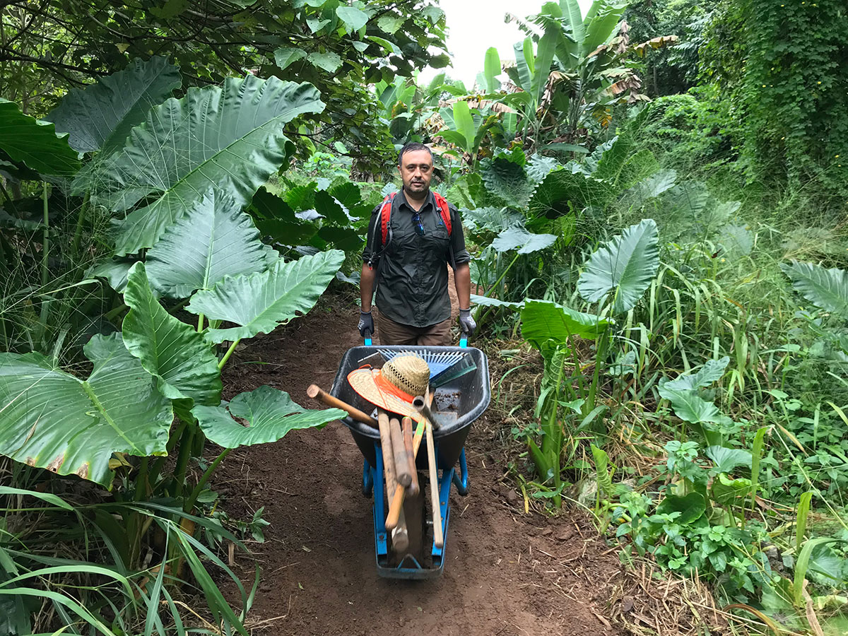 Man with wheelbarrow full of tools on new dirt path
